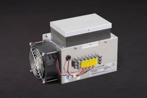 Three-quarter view of thermoelectric cold plate cooler/heater incorporating two thermoelectric modules. Cooled aluminum plate on the front, waste heat is exhausted to fins on back. Fins are fan cooled. The fan air enters on the one end of the fins, travels the length of the fins, and exhausts out the opposite side. Operates on 24 volts DC and removes 59 watts of heat at a 0°C temperature difference relative to ambient. Internal extender blocks improves the heat pumping capacity at larger temperature differences. Can heat to 100°C without damaging the cooler.