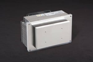 Three-quarter view of thermoelectric cold plate cooler/heater incorporating two large thermoelectric modules. Cooled aluminum plate on the front, waste heat is exhausted to fins on back. High density fins are fan cooled. The fan air enters on the middle back and exhausts on sides. Operates on 24 volts DC and removes 105 watts of heat at a 0°C temperature difference relative to ambient. Internal extender blocks improve the heat pumping capacity at larger temperature differences.